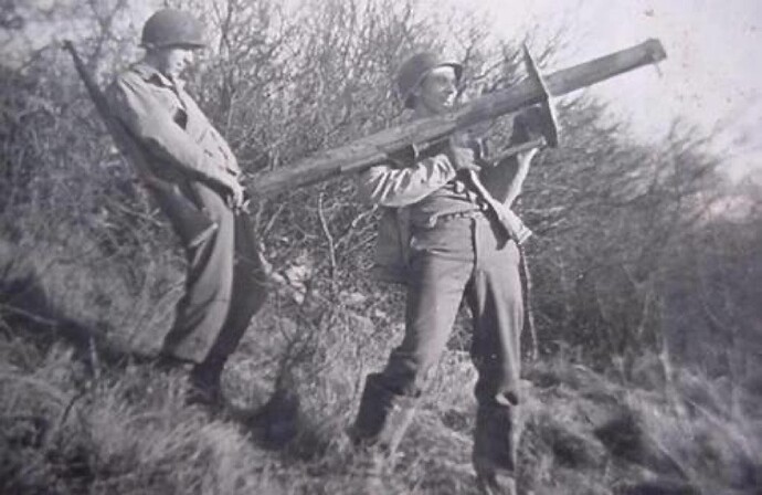 Two American soldiers. One holding a rocket launcher up while the other one stands behind it pretending it's his dick.